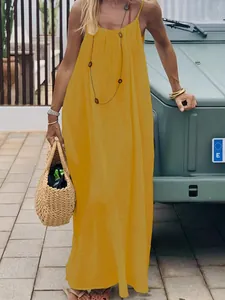 Model wearing a vibrant yellow loose maxi camisole dress with backless design outdoors.