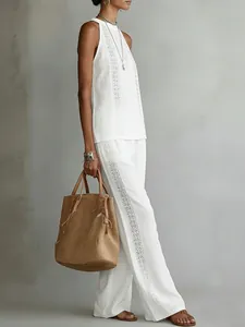 Side view of women's white lace sleeveless top and wide-leg pants set on model