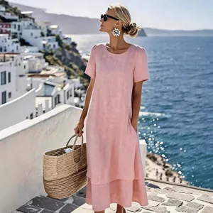 Close-up of a pink double-layer linen vacation dress worn by a model on a coastal street