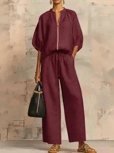 Detailed view of burgundy tunic set with gold zipper and wide-leg pants texture