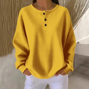 Detailansicht des stilvollen gelben Waffelstrick-Pullovers mit modernem Knopfkragen-Design.