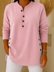 Close-up of pink long sleeve knit top with decorative side buttons and V-neck.