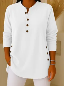 Detail of white knit top featuring V-neck and button accents on a female model.