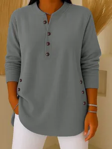 Detailed view of women's grey knit top featuring V-neck buttons and side decorative accents