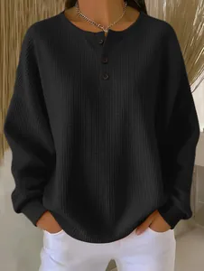 Detailansicht der schwarzen Waffelstrick-Struktur und der Henley-Knopfleiste am Ausschnitt.