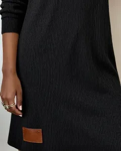 Detalle de primer plano de un vestido negro de punto acanalado con un parche de cuero marrón.