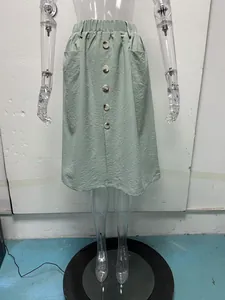 Close-up detail of the green A-line midi skirt showing buttons and elastic waist
