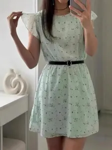 Mint green floral dress with flutter sleeves and a black waist belt for summer.