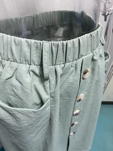 Close-up detail of a light green cargo skirt with elastic waist and button front