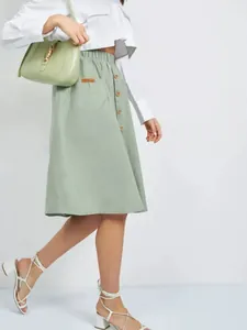 Detail of a light green A-line midi skirt featuring single-breasted buttons and elastic waist.