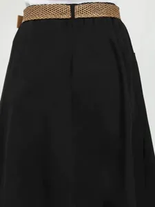 Close-up detail of a women's black A-line midi skirt with elastic waist and woven belt