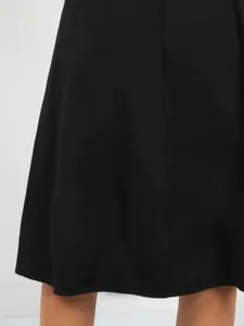 Close-up detail of the smooth hemline on a black A-line midi casual cargo style skirt
