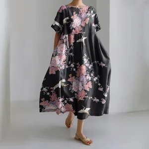 Dettaglio dell'abito lungo nero ampio con eleganti stampe floreali e motivi di gru