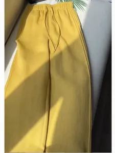 Detailed view of yellow wide-leg trousers with drawstring and textured fabric