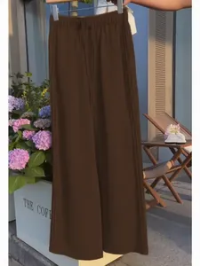 Detailed view of brown wide-leg leisure trousers featuring an elastic drawstring waist