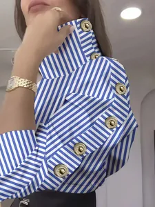 Détail du chemisier à rayures bleues et blanches avec col haut et boutons dorés.