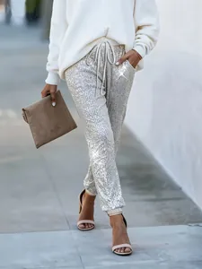 Dettaglio dei pantaloni jogger con paillettes argento da donna con un effetto luce