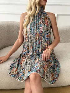 Detailed view of bohemian pleated halter neck dress with vibrant paisley print on model.