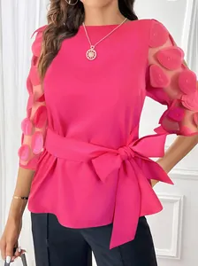 Detalle de top fucsia con pétalos 3D en mangas de malla y gran lazo en la cintura