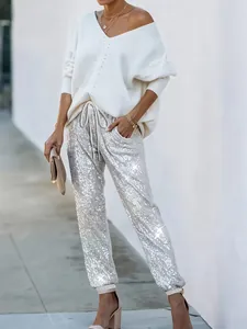 Dettaglio di eleganti pantaloni con paillettes argento abbinati a un maglione bianco