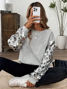 Dettaglio di una felpa grigia festiva con grandi paillettes argentate sulle maniche lunghe