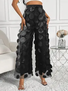 Detail view of elegant black wide-leg mesh trousers featuring unique 3D circular appliques