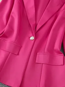 Nahaufnahme eines eleganten pinkfarbenen Blazers mit Zierknopf und Pattentaschen.