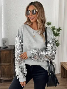 Dettaglio di una felpa grigia casual con maniche lunghe con paillettes d'argento.