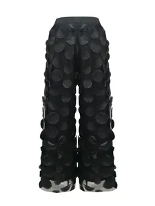 Detail view of black wide-leg trousers with 3D textured polka dot appliques.