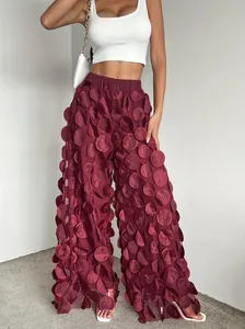 Detail view of burgundy wide-leg trousers with unique 3D mesh circular appliqués