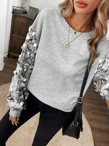 Vista dettagliata delle maniche con paillettes argento scintillanti su felpa grigia da donna.