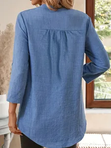Gros plan du dos d'une chemise en lin bleu avec des plis fins et une coupe ample.