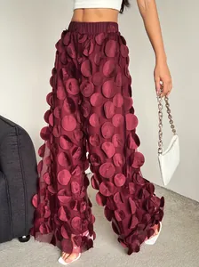 Detail view of burgundy wide-leg trousers featuring unique 3D mesh polka dot applique design