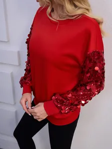Primo piano delle maniche della felpa rossa adornate con scintillanti paillettes rosse.