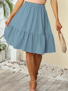 Detail view of light blue ruffled tiered summer mini skirt worn by model with straw bag