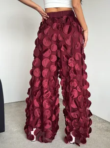Detailed view of maroon mesh trousers featuring elegant 3D circular fabric textures.