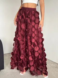 Detailed shot showing the unique 3D circular fabric appliqués on burgundy mesh trousers.