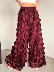 Detailed view of burgundy wide-leg trousers featuring unique 3D circular mesh appliques.