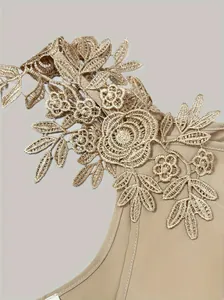 Close-up of elegant gold floral lace embroidery on an off-shoulder beige T-shirt.