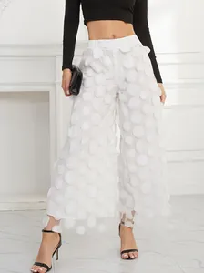 Detail view of elegant white mesh wide-leg pants with 3D applique polka dots.