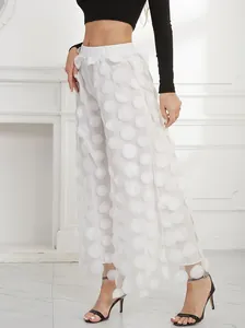 Close-up detail of elegant white mesh wide-leg trousers with 3D textured polka dots for women.