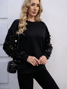 Dettaglio della felpa nera con eleganti maniche impreziosite da paillettes su modella
