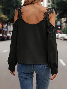 Detail view of black cold shoulder top featuring intricate floral lace straps on model's back.