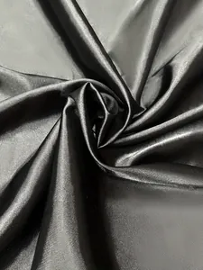 Gros plan sur un tissu satiné noir élégant avec un éclat soyeux luxueux et un beau drapé.
