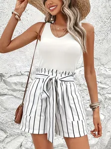 Stylish woman in white ribbed tank top and striped high-waist shorts for summer beach look