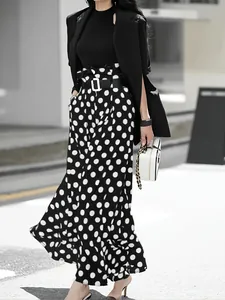 Detail view of stylish high-waisted black and white polka dot wide-leg trousers for women
