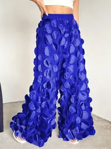 Detailed close-up of 3D floral petal mesh embellishments on vibrant blue wide-leg trousers