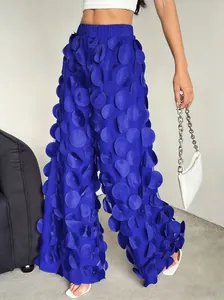 Detail of royal blue wide-leg trousers featuring a unique 3D circle applique polka dot design.