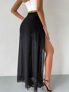 Detail of black double-layered mesh maxi skirt with side split and glitter accents