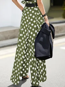 Detailed view of stylish high-waisted green and white polka dot wide-leg trousers.